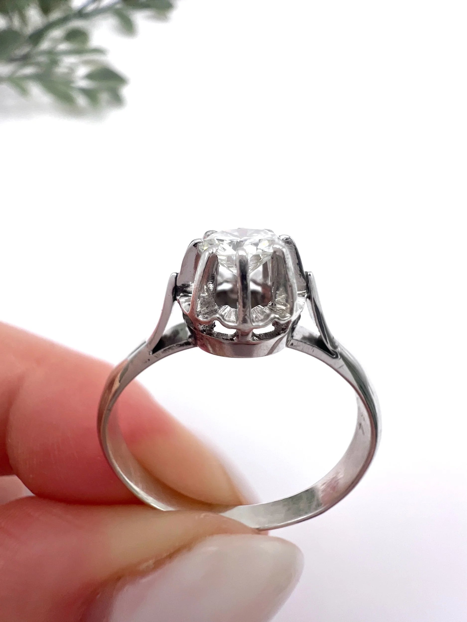 A solitaire round diamond ring in white gold, held in a hand