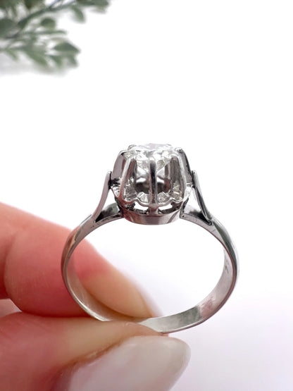 A solitaire round diamond ring in white gold, held in a hand