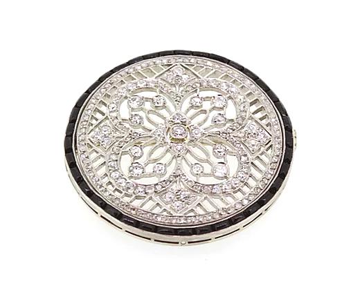 Art Deco Diamond Onyx and Platinum Circular Brooch; featuring a diamond-set floral and geometric design, surrounded by a halo of calibre-cut onyx.