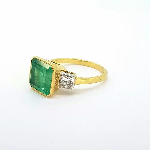 Octagonal Cut Emerald and Diamond Three Stone Ring; 5.00 carat octagonal step-cut emerald flanked by 0.80cts square princess cut diamonds, 18ct yellow gold