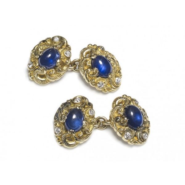 Sapphire and Diamond Carved Gold Cufflinks; double sided cufflinks with each side featuring a central oval cabochon-cut sapphire accented with three old-cut diamonds, mounted in carved gold scroll work, with chain fittings