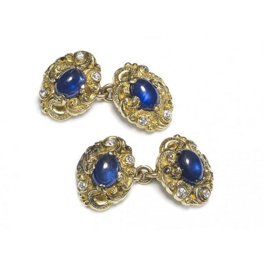 Sapphire and Diamond Carved Gold Cufflinks; double sided cufflinks with each side featuring a central oval cabochon-cut sapphire accented with three old-cut diamonds, mounted in carved gold scroll work, with chain fittings