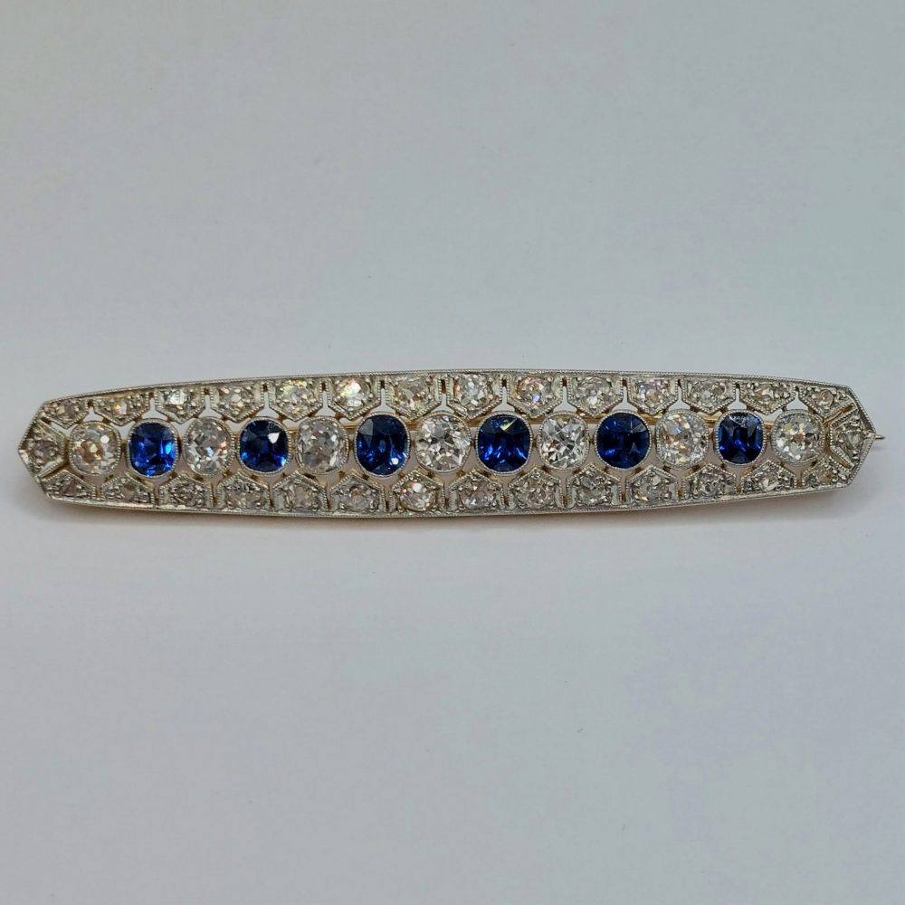 Antique Sapphire and Old Cut Diamond Bar Brooch; featuring a line of alternated oval blue sapphires and old mine-cut diamonds, all surrounded by rose cut diamonds in an openwork platinum mount with millegrain edging and backed with 15ct yellow gold. Sapphires 1.00 carat, Diamonds 1.75 carats