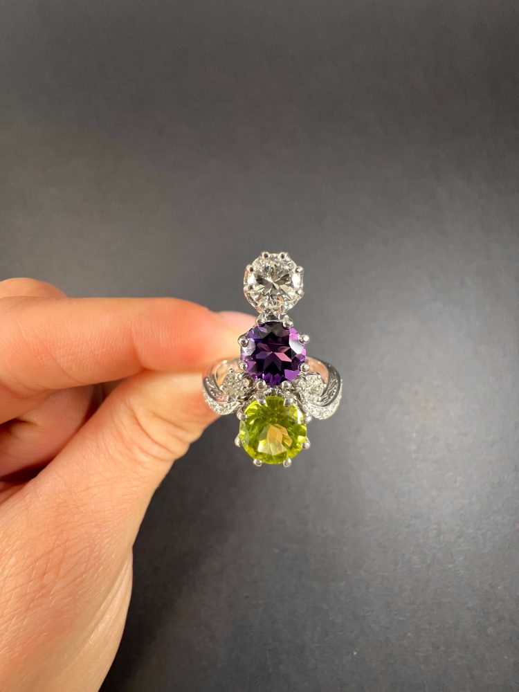 Edwardian Antique French Suffragette Amethyst Peridot Diamond Three Stone Ring, graduating trilogy of peridot amethyst and diamond arranged vertically up the finger when worn in 18ct white gold on diamond-set band with French eagles head stamp