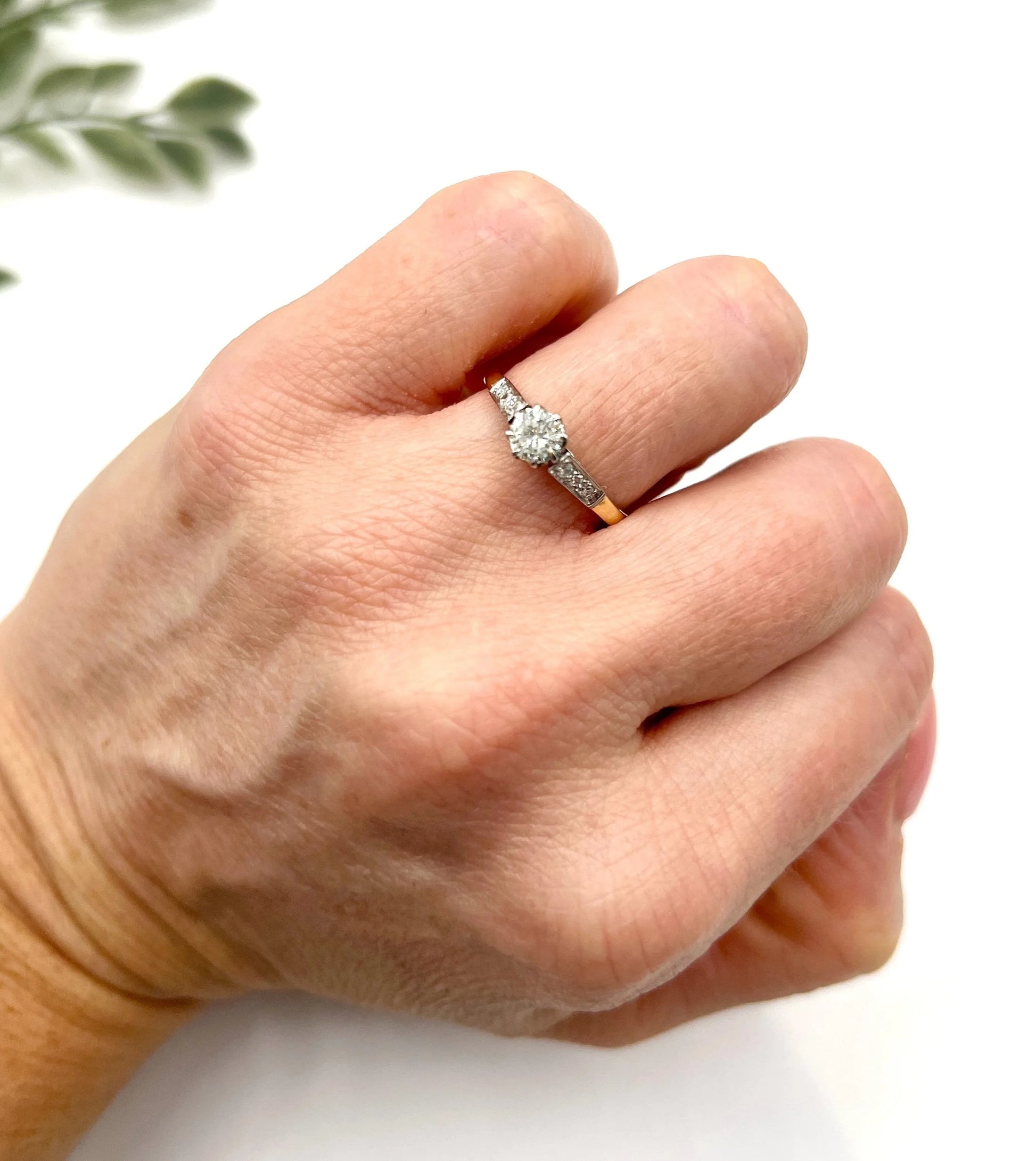A diamond engagement style ring in yellow gold and platinum, modelled on a hand