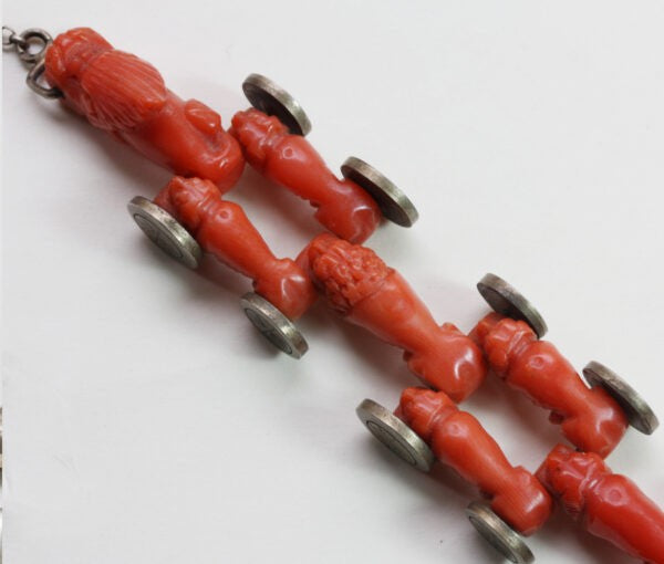 Antique Georgian Coral Bracelet; with ten carved animal coral links of a lion, dogs, dragons head and tail, with gold charm lock, 19th century
