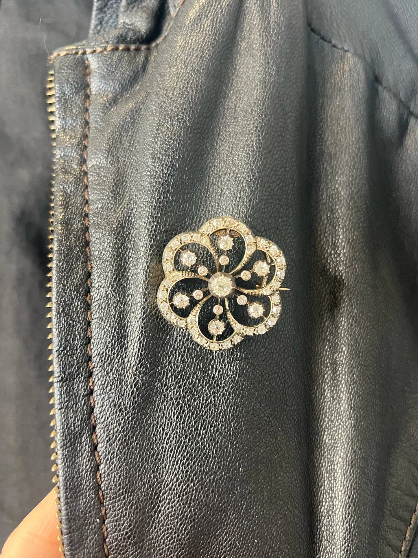 A floral design diamond set pendant/brooch, modelled on a black jacket