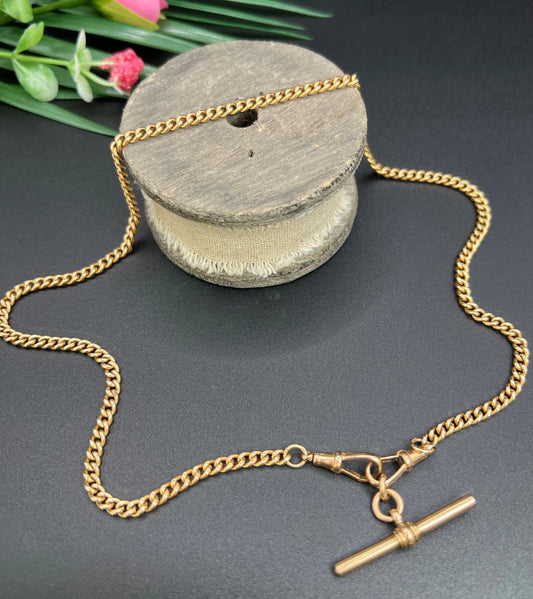 A gold curb link Albert chain, on a wooden spool