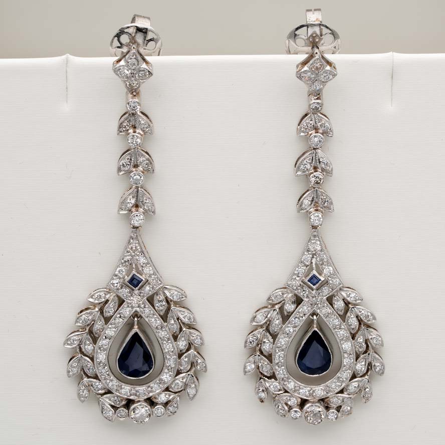 Edwardian Belle Epoque Antique Sapphire and Diamond Cluster Drop Earrings in Platinum, pear-shaped blue sapphires suspended within diamond wreath clusters from diamond leaf work drops, Circa 1905