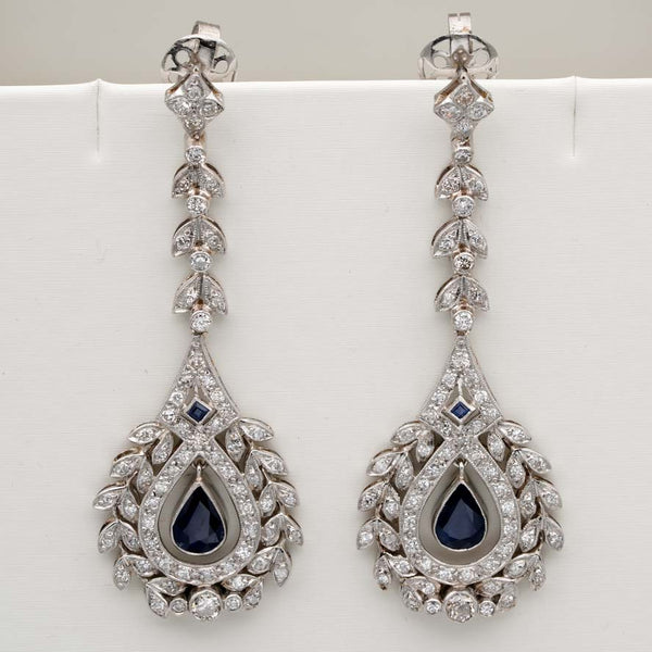 Edwardian Belle Epoque Antique Sapphire and Diamond Cluster Drop Earrings in Platinum, pear-shaped blue sapphires suspended within diamond wreath clusters from diamond leaf work drops, Circa 1905