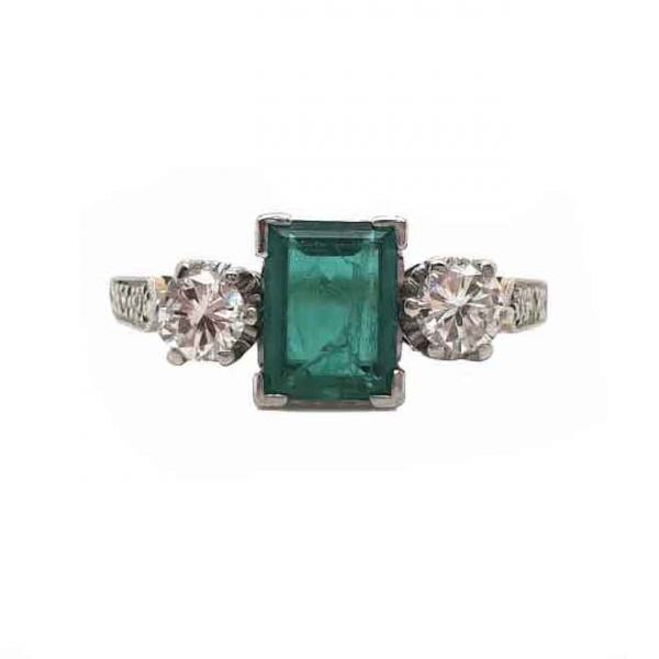 Vintage Emerald and Diamond Three Stone Engagement Ring; 0.60ct baguette-cut emerald flanked by brilliant cut diamonds, diamond set shoulders, 18ct yellow gold, Circa 1940s