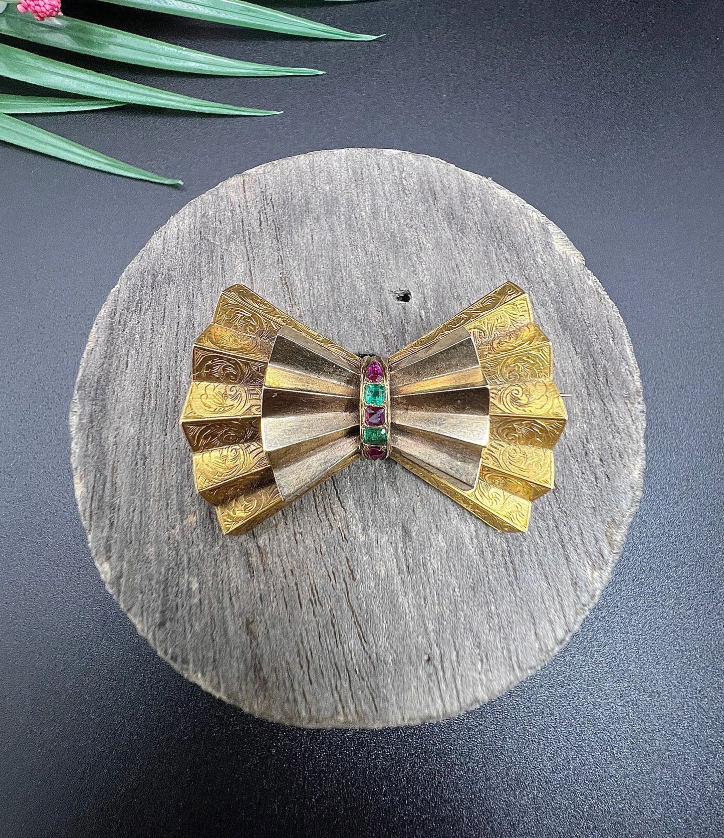 A yellow gold bow shaped brooch with rubies and emeralds