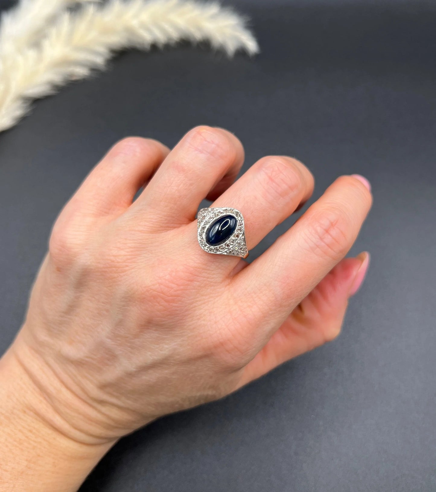 An oval cabochon sapphire and diamond fancy cluster ring in yellow and white gold, modelled on a hand