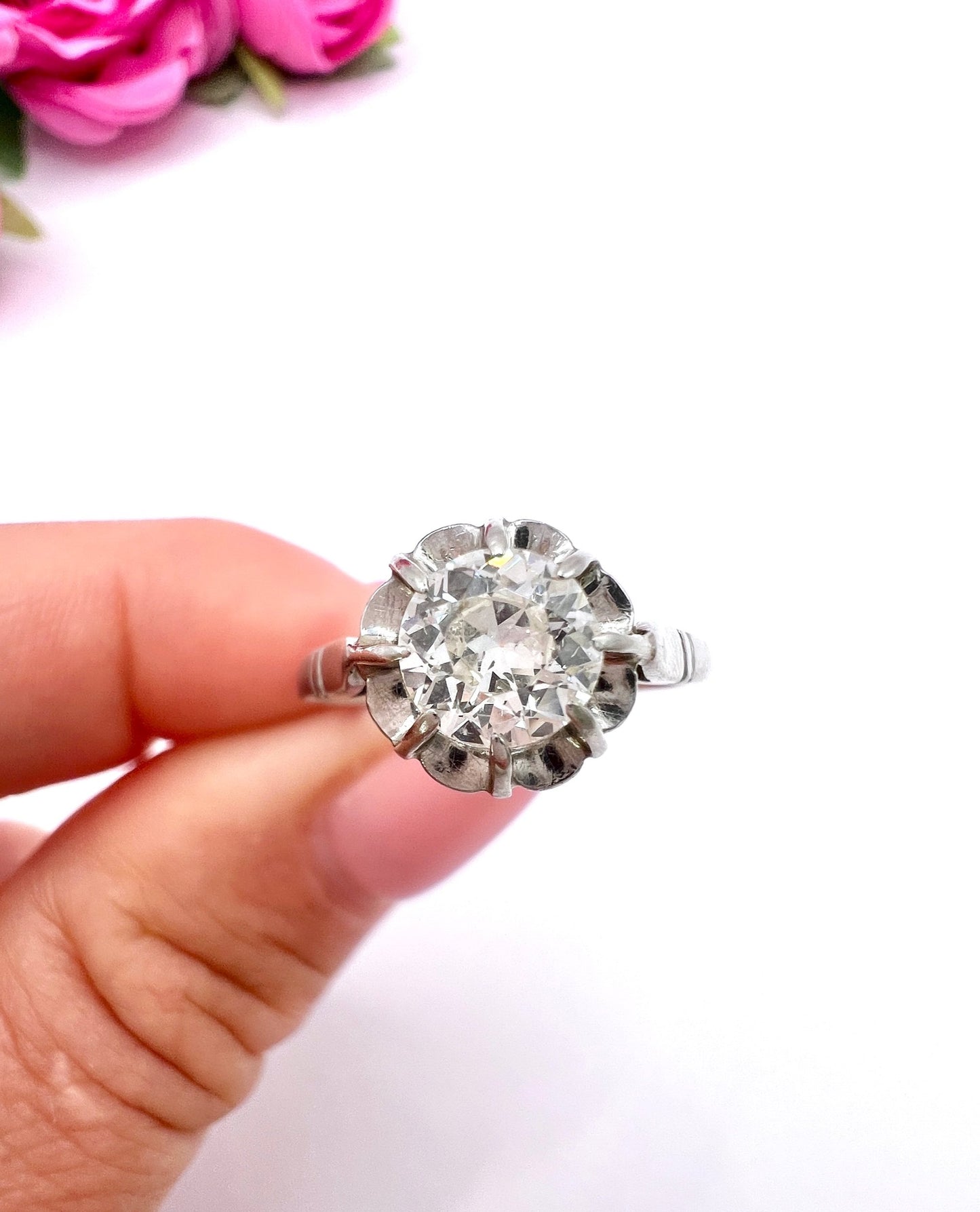 A solitaire diamond ring in platinum, held in a hand