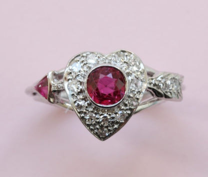 Vintage 1950s Ruby and Diamond Heart and Arrow Ring; 0.75ct round old-cut ruby surrounded by 0.30cts diamonds, in platinum and white gold