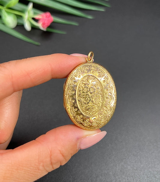 An oval floral engraved locket, held in a hand