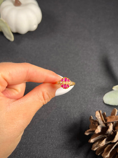 A yellow gold ruby and pearl cluster ring, held in a hand