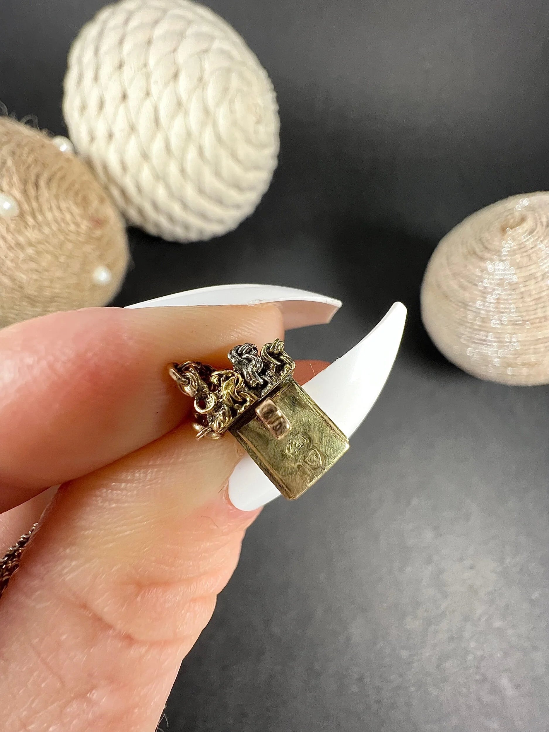 Close-up of a gold bracelet clasp with a stamp, held in a hand