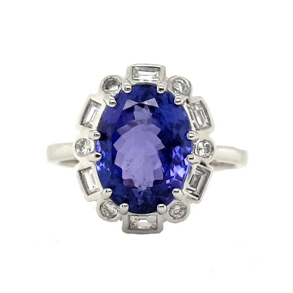 Tanzanite and Diamond Cluster Dress Ring; central 4.56 carat oval faceted tanzanite surrounded by alternating brilliant-cut and baguette-cut diamonds, in 18ct white gold