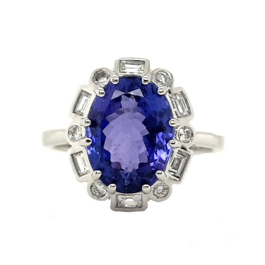 Tanzanite and Diamond Cluster Dress Ring; central 4.56 carat oval faceted tanzanite surrounded by alternating brilliant-cut and baguette-cut diamonds, in 18ct white gold