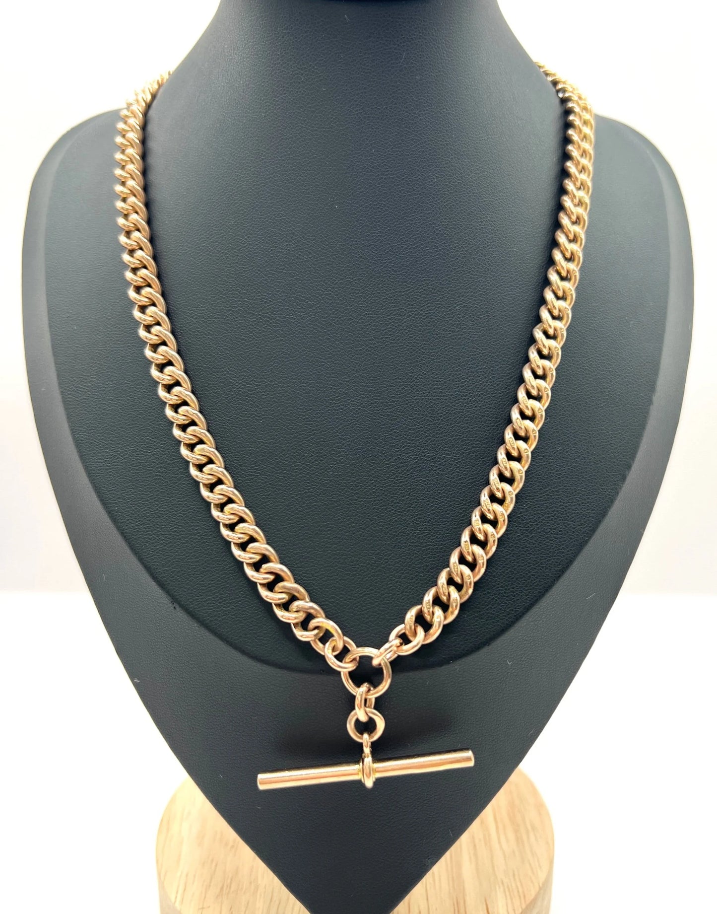 A rose gold curb link Albert chain on a black jewellery bust