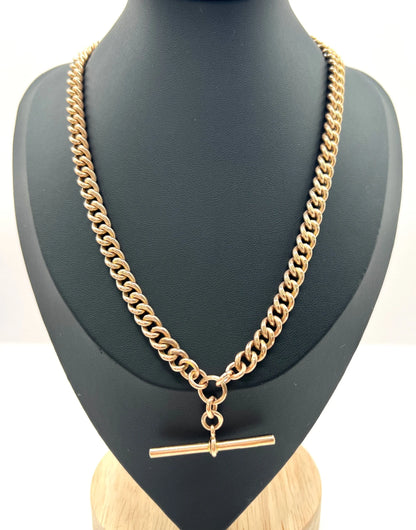 A rose gold curb link Albert chain on a black jewellery bust
