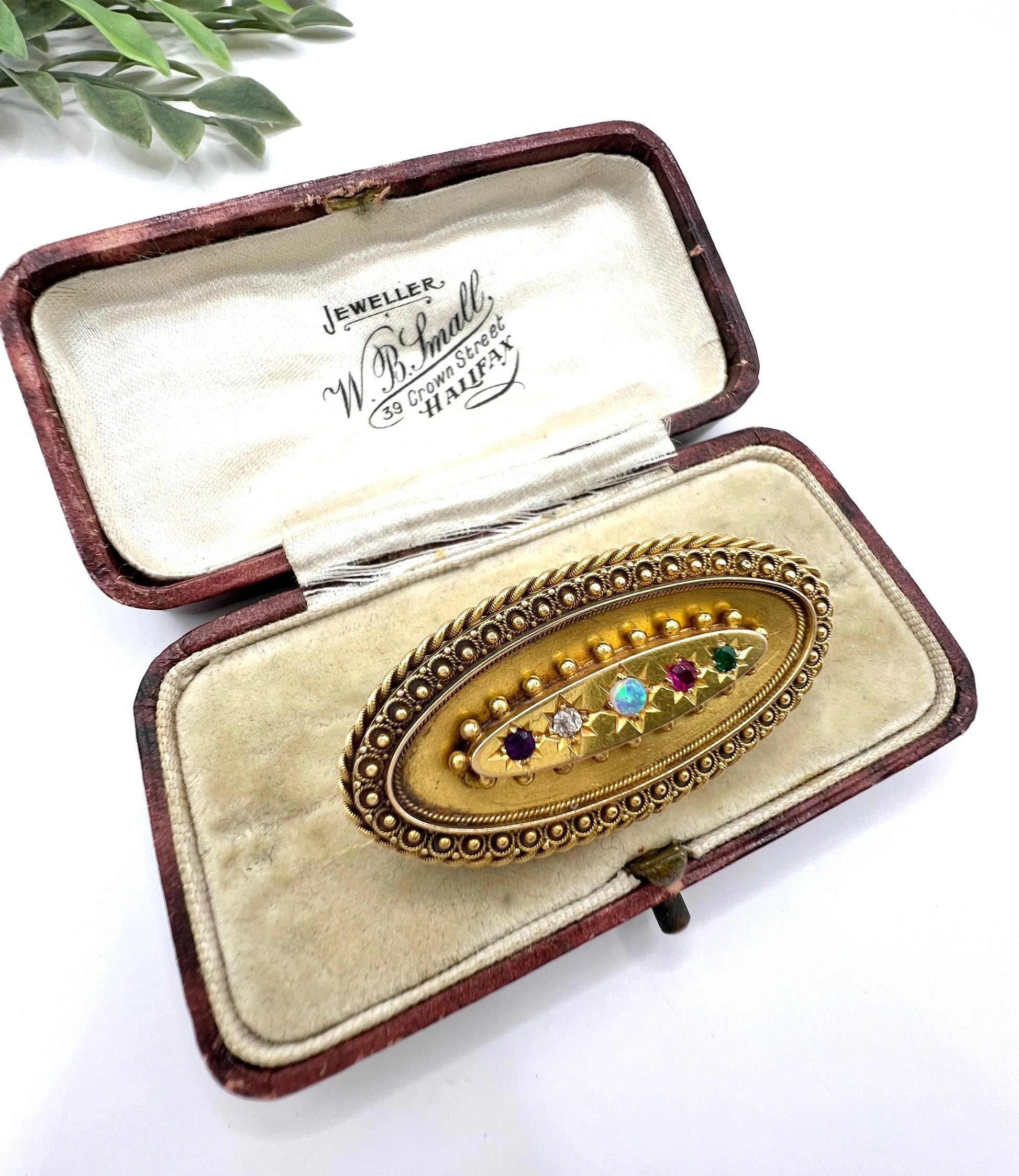 An oval yellow gold multi-gemstone acrostic brooch, in an antique box