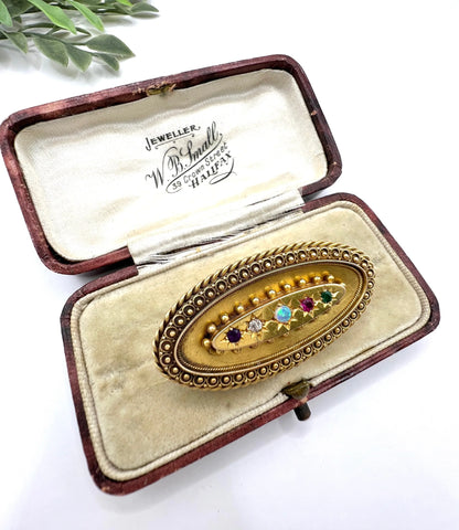 An oval yellow gold multi-gemstone acrostic brooch, in an antique box