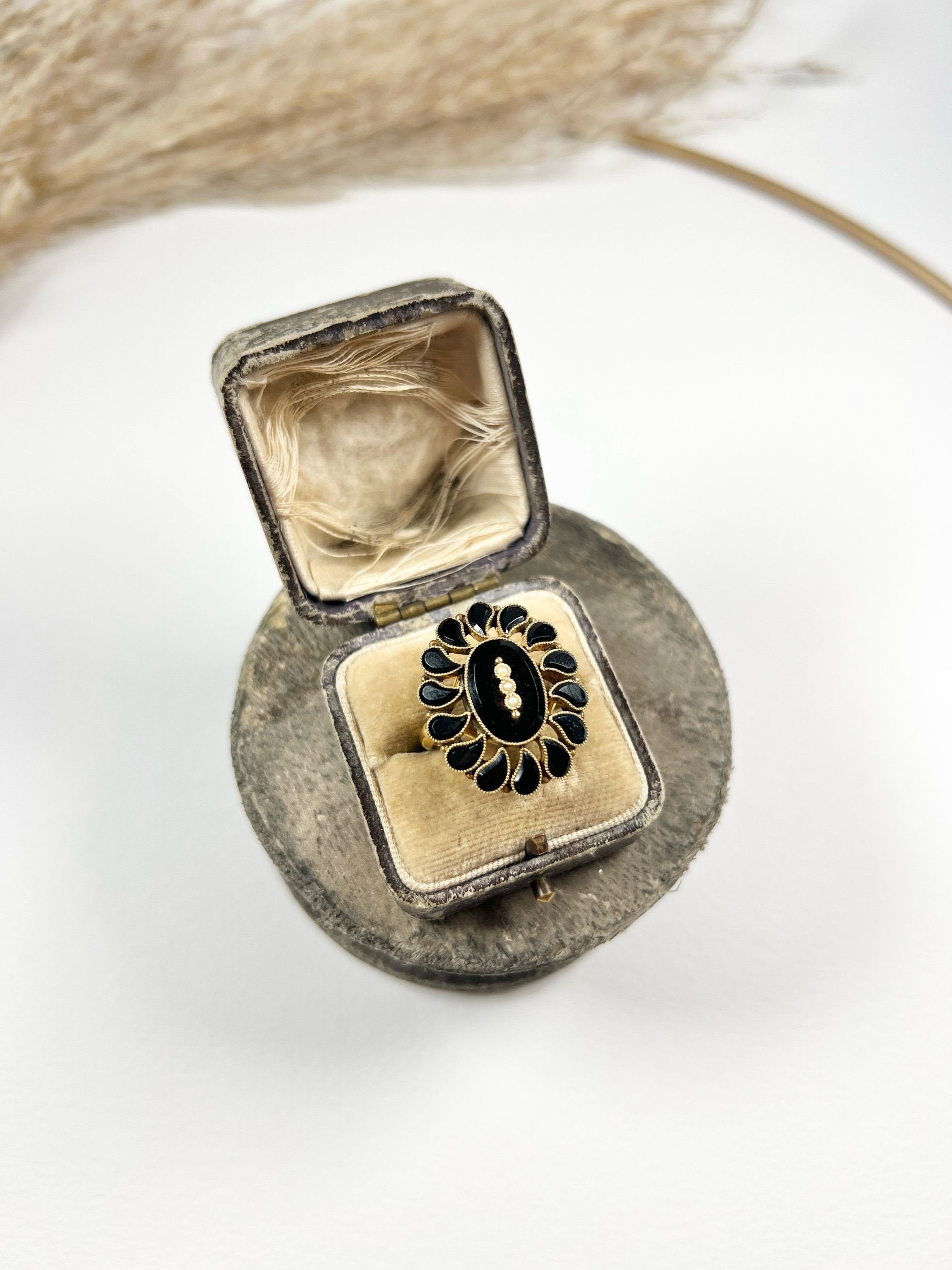 A black onyx and seed pearl fancy halo cluster ring in yellow gold, in a ring box
