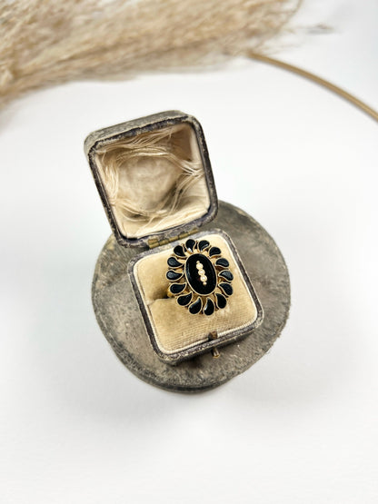 A black onyx and seed pearl fancy halo cluster ring in yellow gold, in a ring box