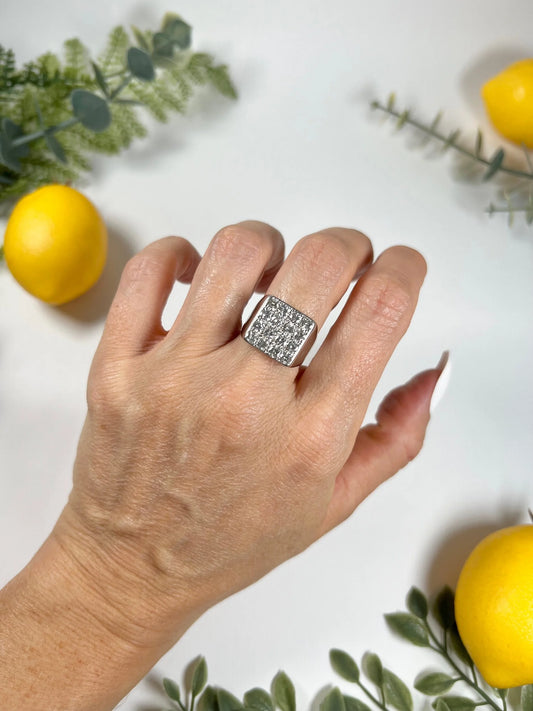 A square shaped diamond cluster ring in white gold, modelled on a hand