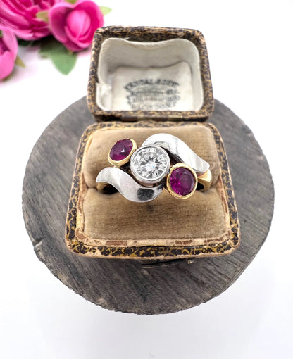 A three stone ruby and diamond crossover ring in platinum and yellow gold, in a ring box
