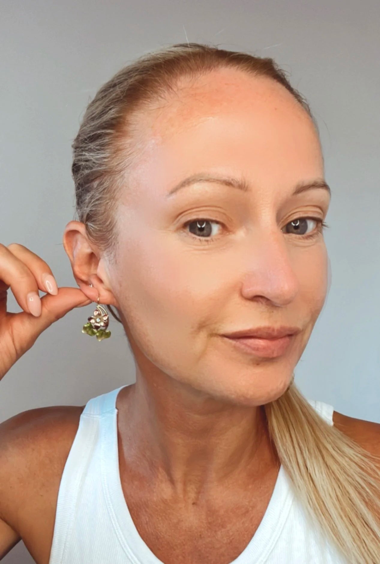 Gold and enamel diamond flower earring modelled by a lady wearing a white top