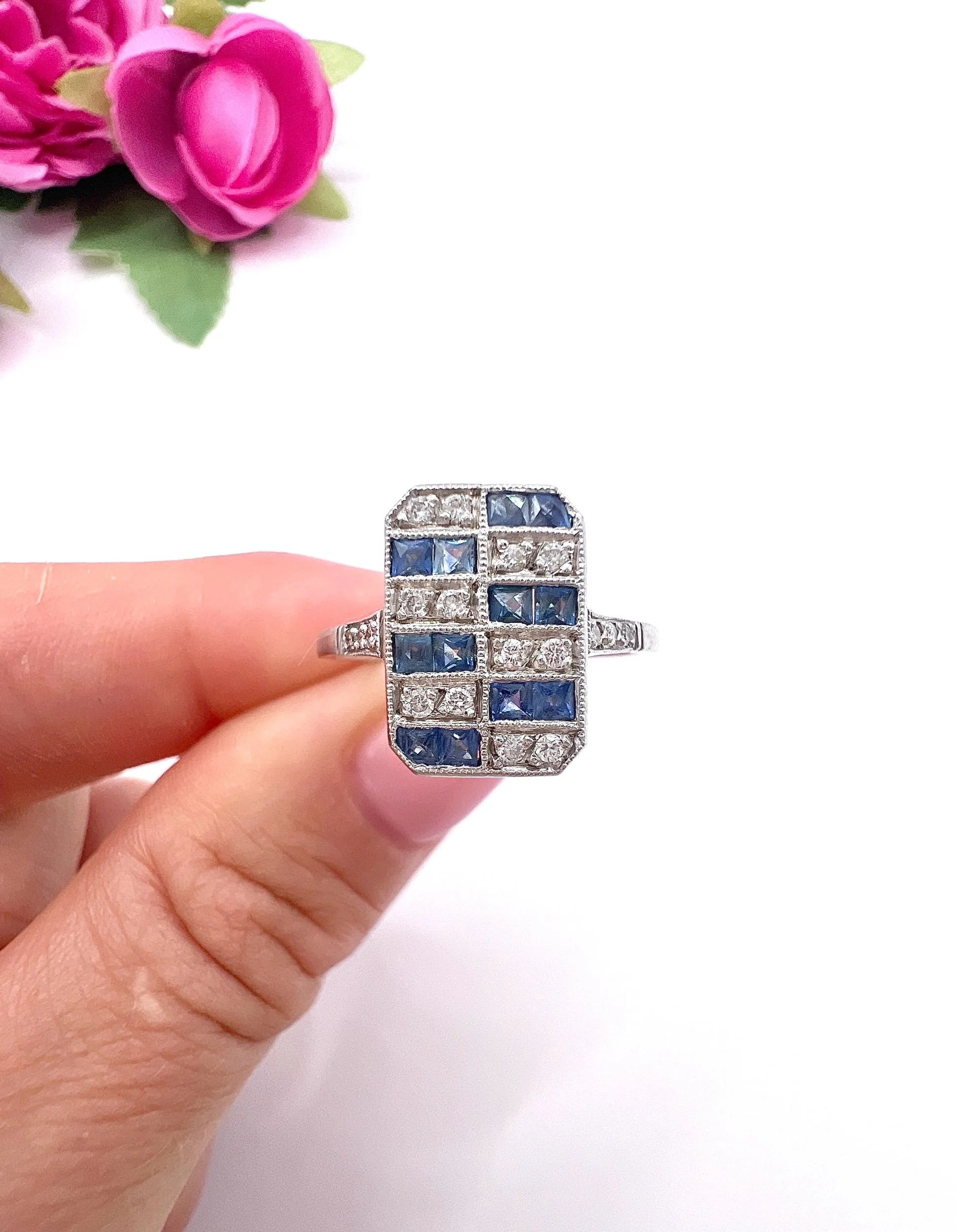 A sapphire and diamond tablet style ring in platinum, held in a hand