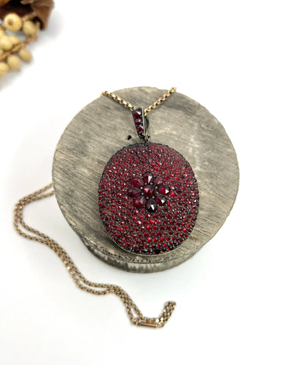 An antique oval locket encrusted with garnets, with a chain