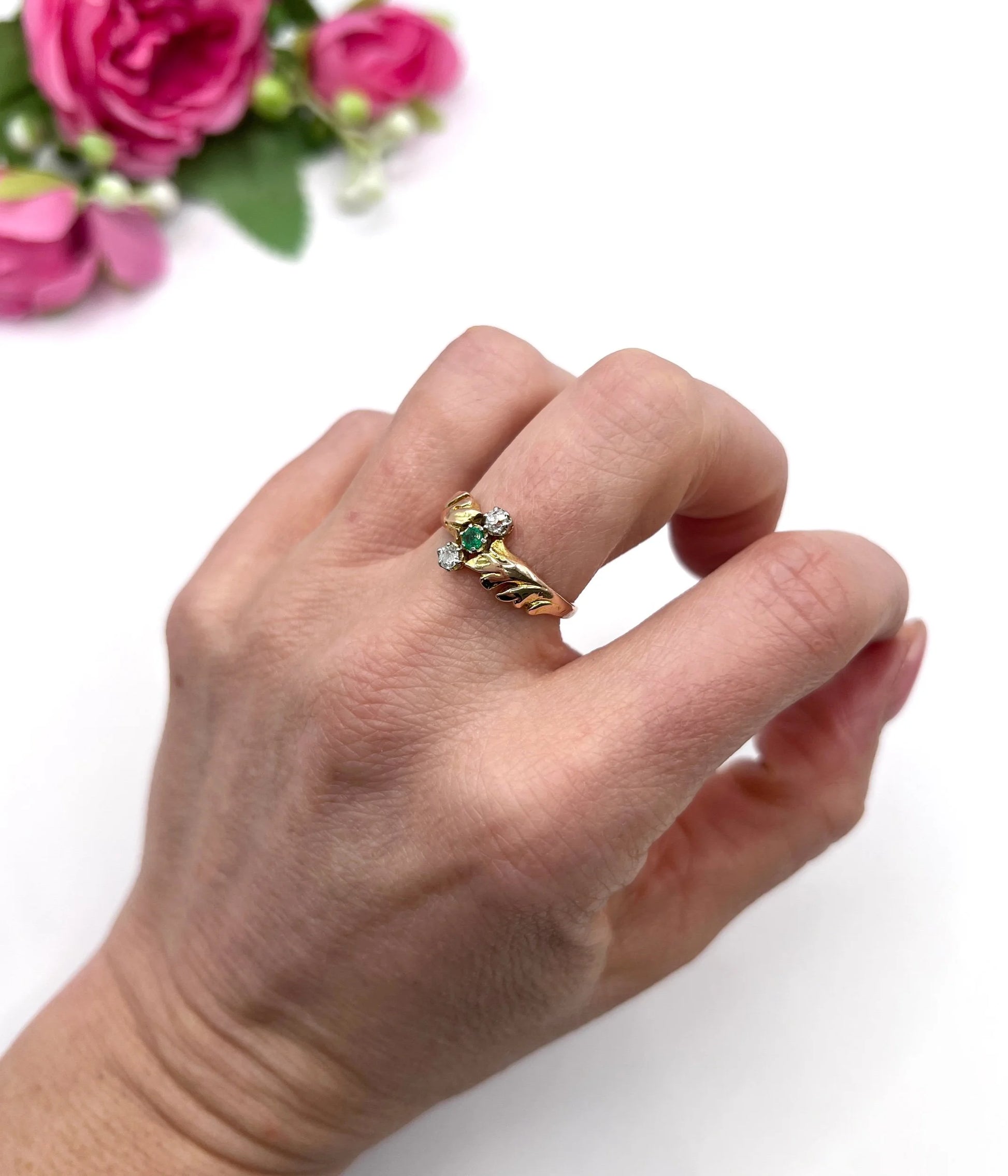 A three stone emerald and diamond ring in yellow and white gold, modelled on a hand