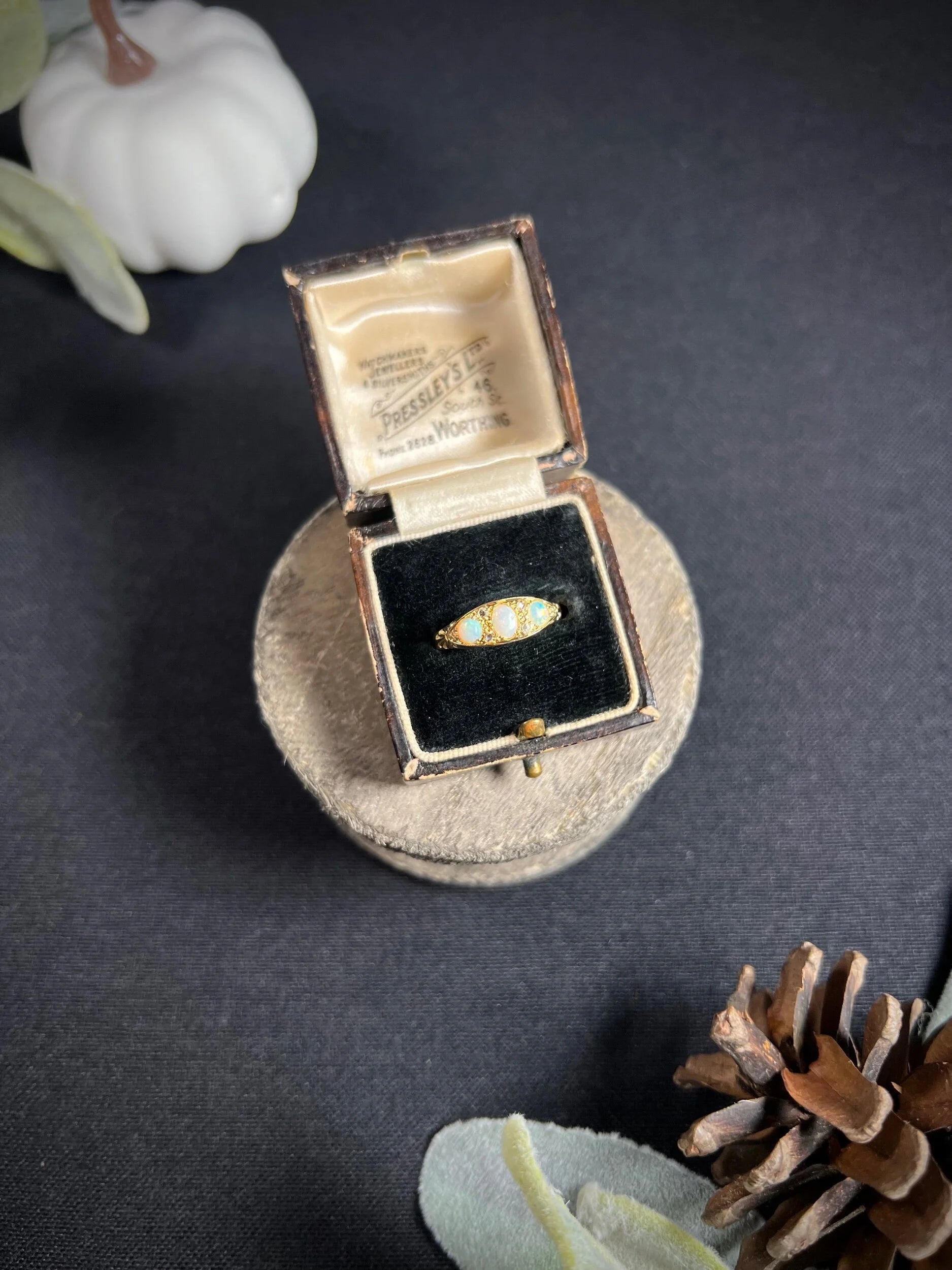 A boat-shaped gold ring with opals and diamonds, in a ring box