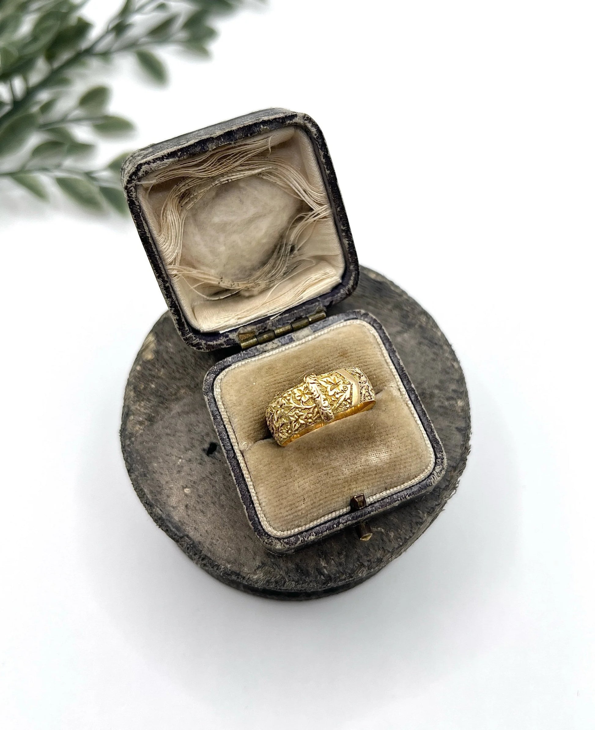 A yellow gold ornate engraved buckle band ring, in an antique ring box