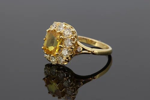 Yellow Sapphire and Diamond Cluster Ring; 2.90ct octagonal cut yellow sapphire surrounded by 1.35cts diamonds, accented with diamond set split shoulders, mounted in 18ct yellow gold.
