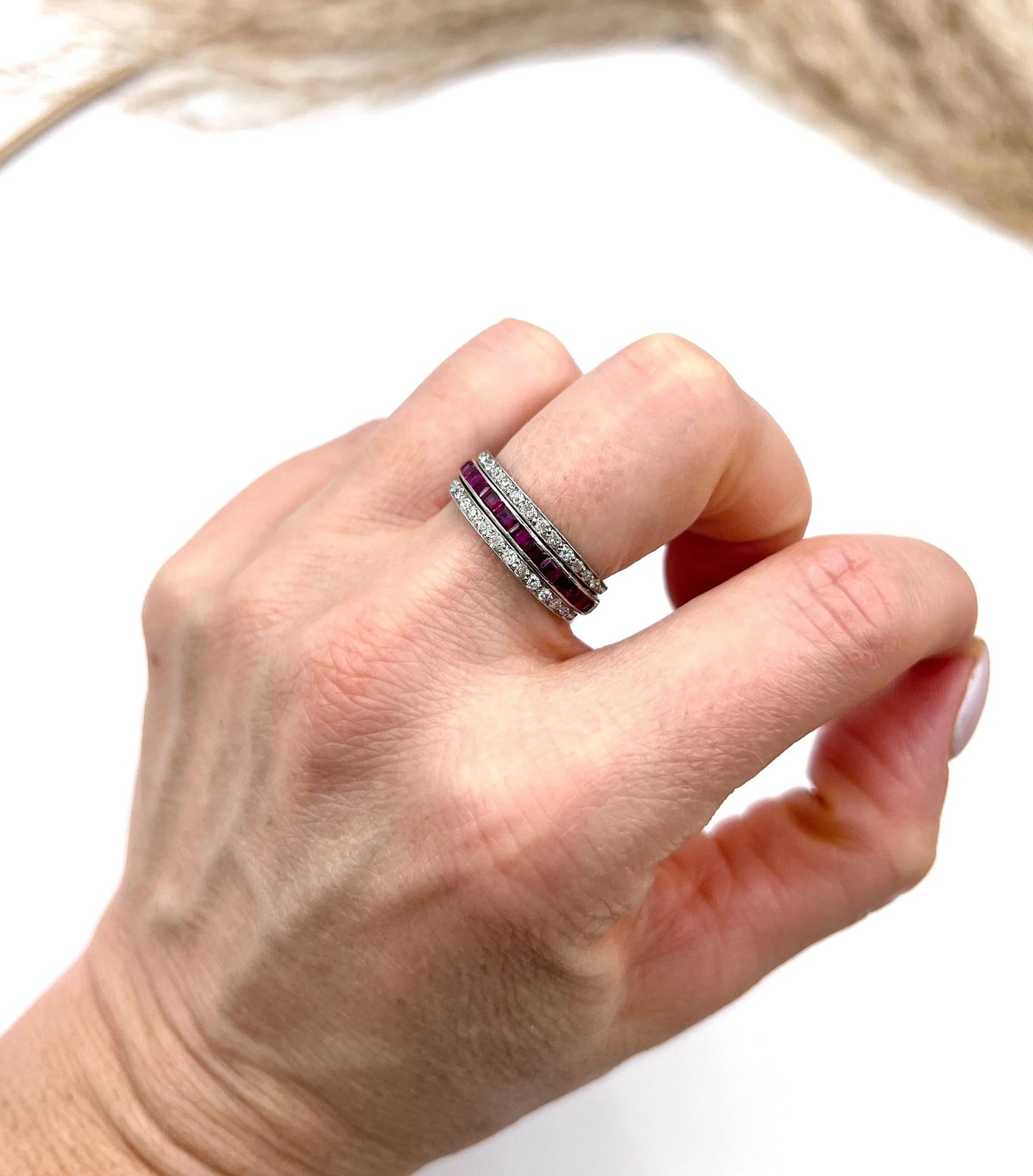 A platinum night and day flip band ring set with diamonds, sapphires and rubies, modelled on a hand