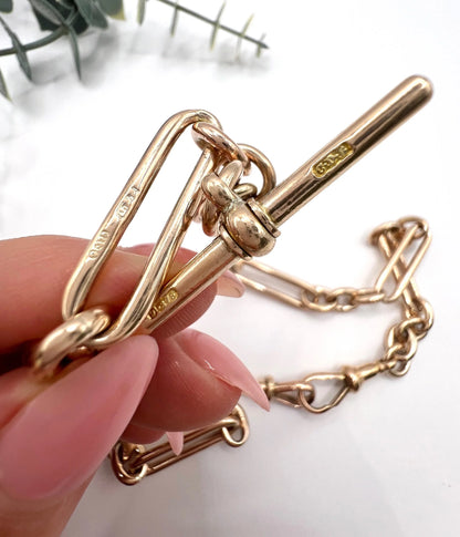 Close-up of a rose gold T-bar and trombone link, held by a hand