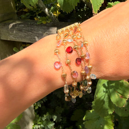 A yellow gold five row multi-gemstone bracelet, modelled on a wrist