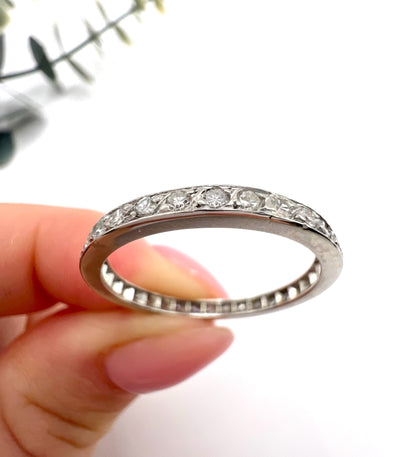 A platinum and diamond full eternity band ring, held in a hand