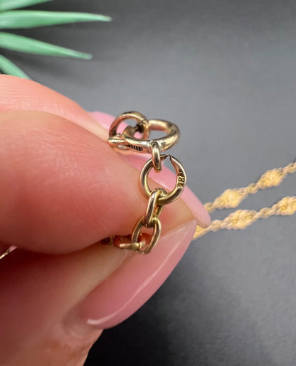 A yellow gold fancy link chain necklace, close-up of the 18 stamp on the end ring