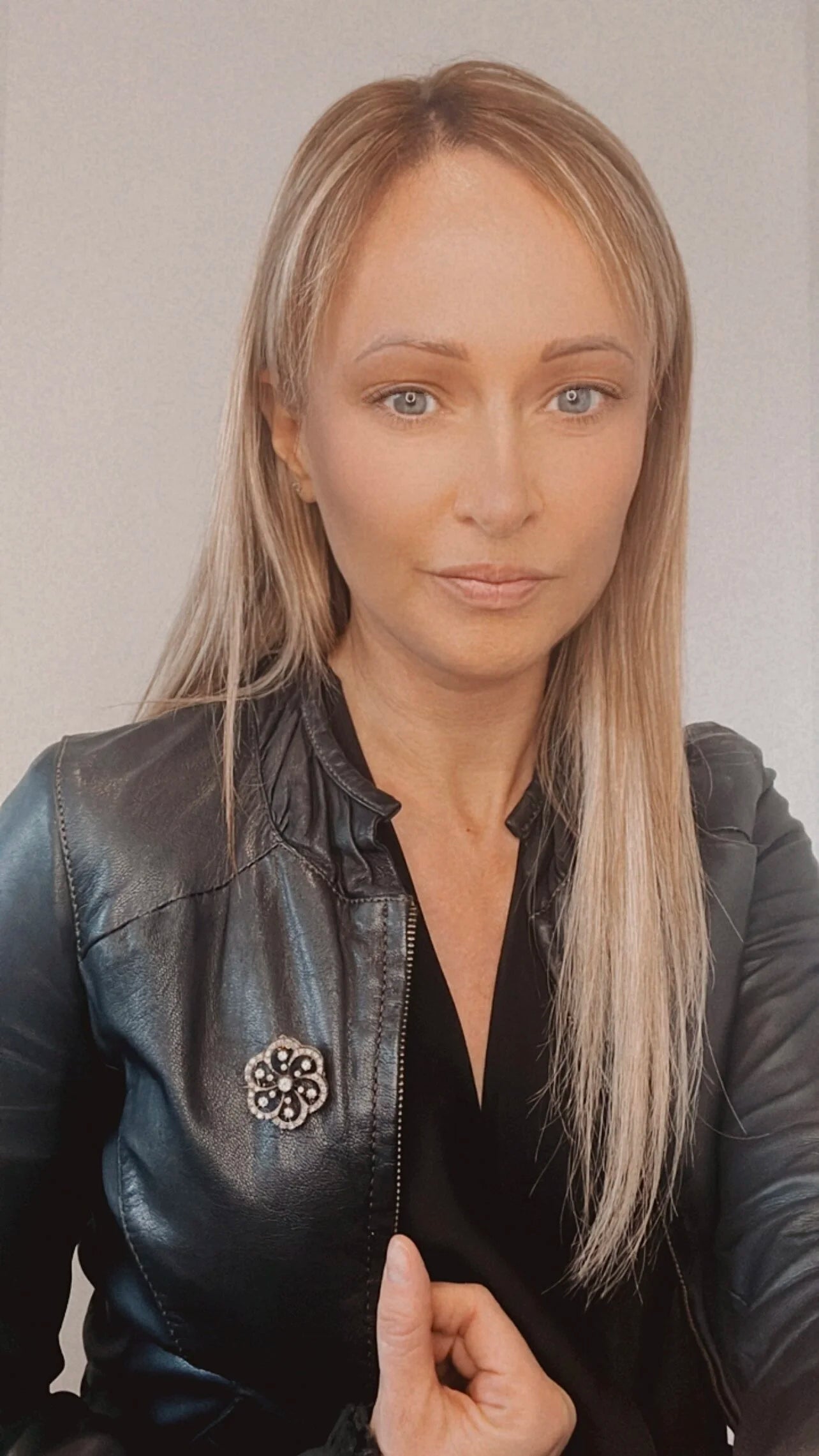 A floral design diamond set pendant/brooch, modelled by a lady wearing a black jacket