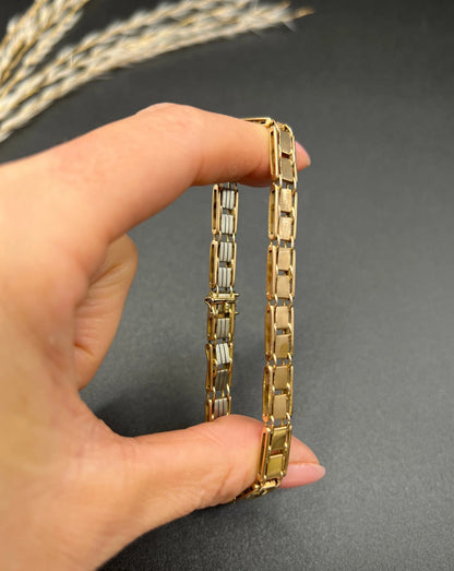 A gold and platinum gate bracelet, held in a hand