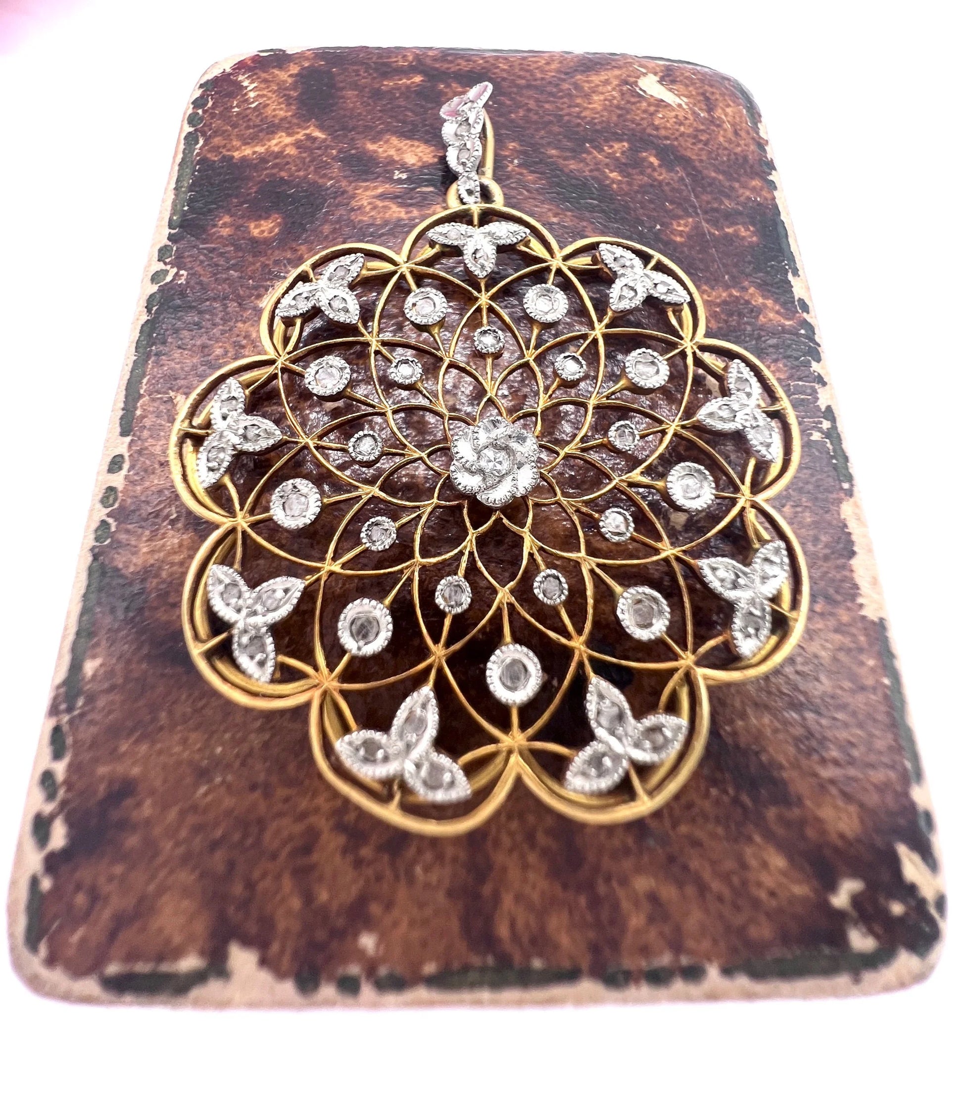 A floral openwork diamond pendant in gold and platinum