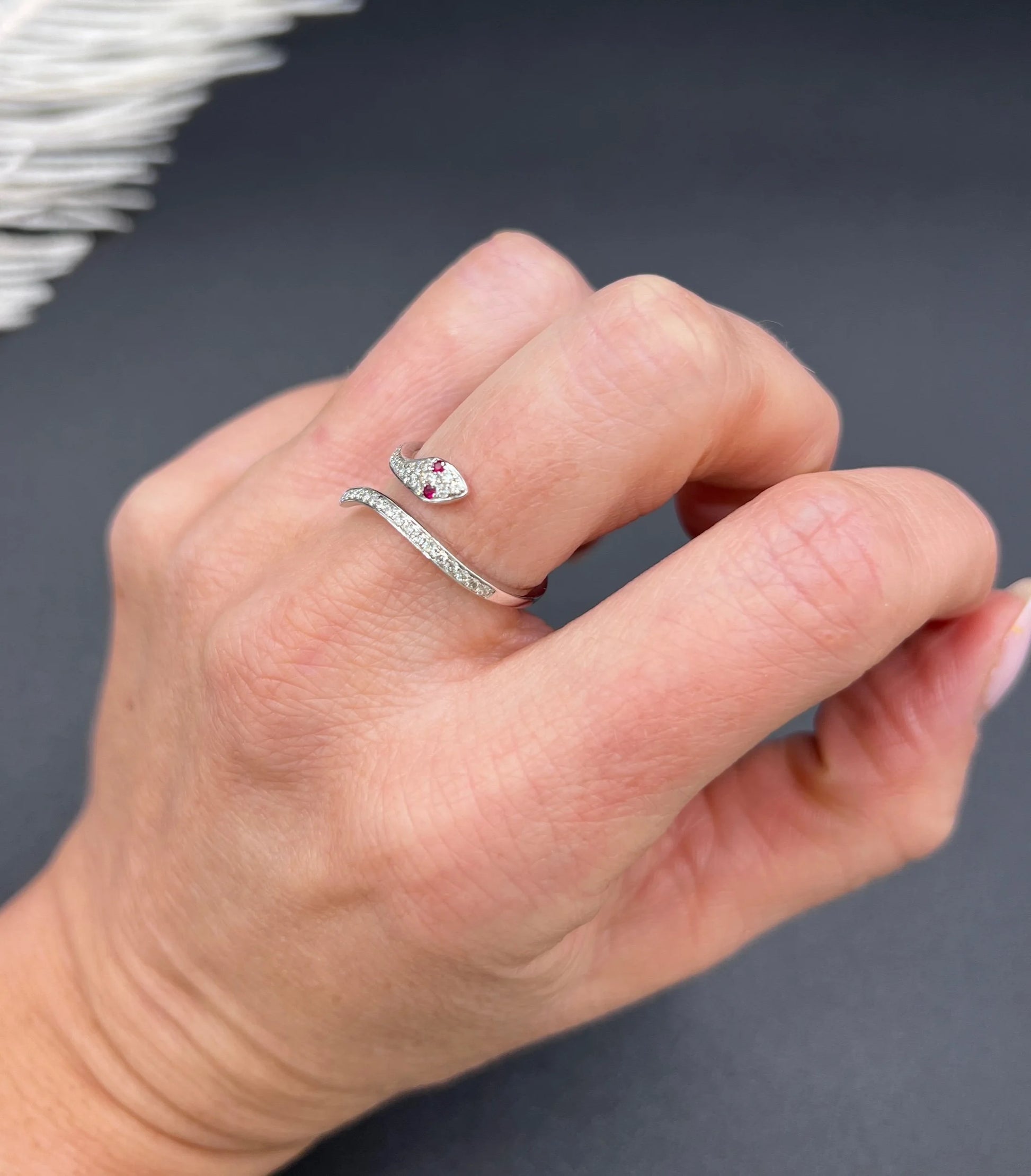 A white gold snake ring set with diamonds and with ruby eyes, modelled on a hand