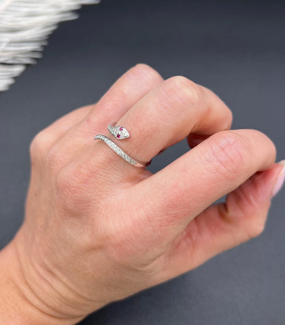 A white gold snake ring set with diamonds and with ruby eyes, modelled on a hand