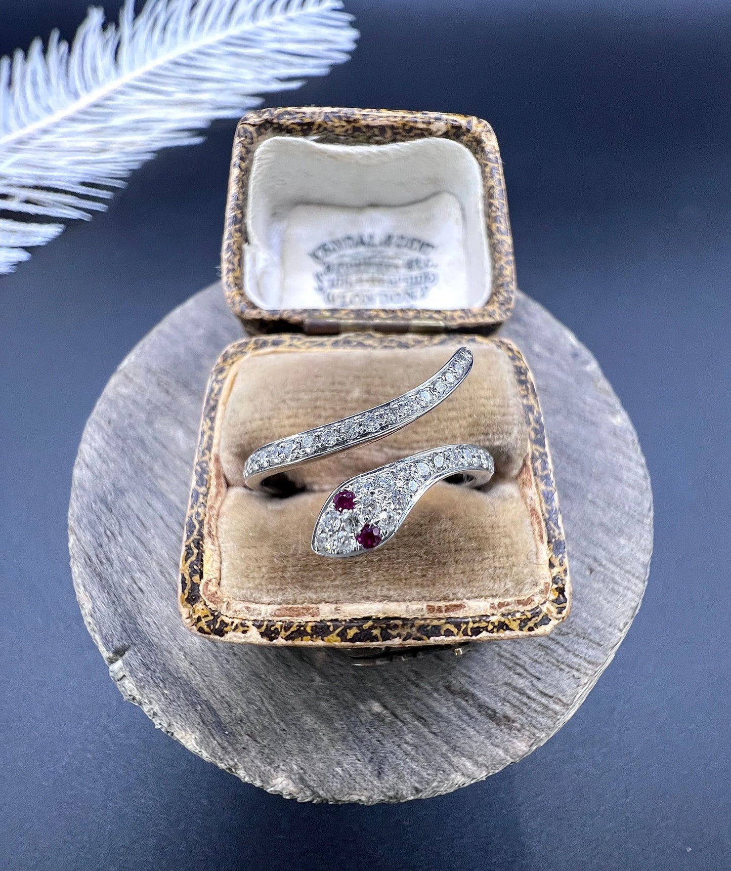 A white gold snake ring set with diamonds and with ruby eyes, in an antique ring box